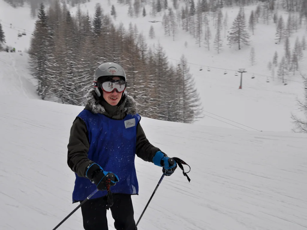 Jugendlicher mit Skibrille steht auf der Piste im Schneetreiben.